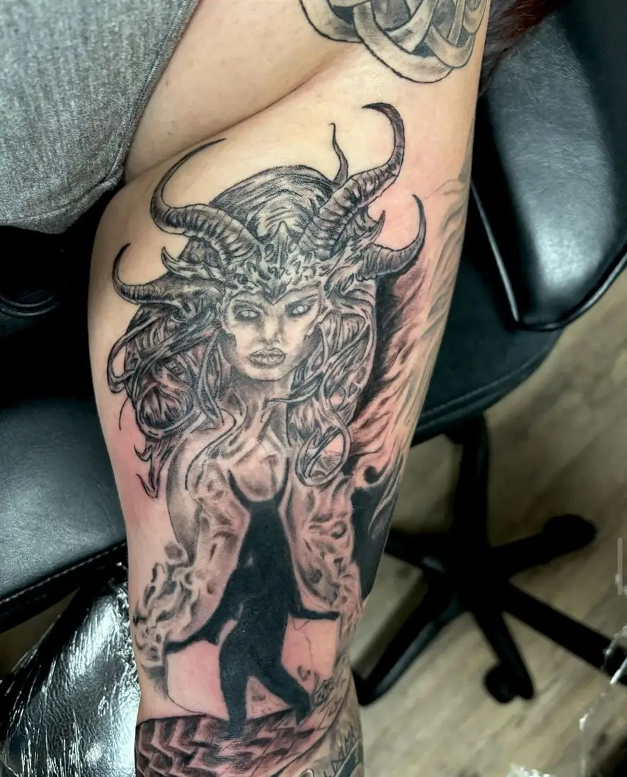 Black and grey horned demon woman tattoo on the upper arm