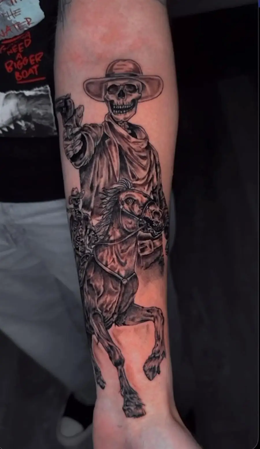Black and grey forearm sleeve tattoo of a skeleton cowboy riding a skeleton horse