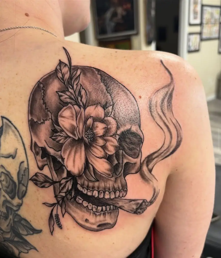 Black and grey skull with hibiscus flower and smoke tattoo on the shoulder blade
